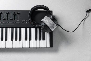 Photo of MIDI keyboard with headphones on white table, top view