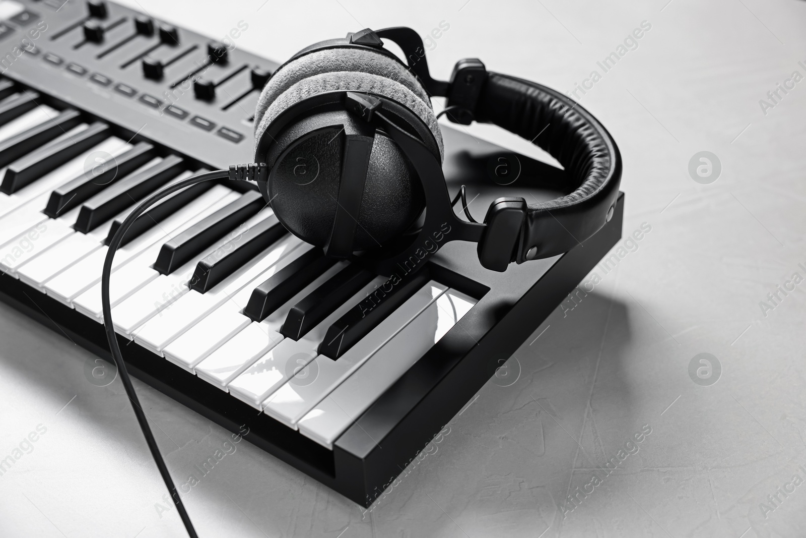 MIDI keyboard with headphones on white table, closeup. Space for text Photo of MIDI keyboard with headphones on white table, closeup. Space for text