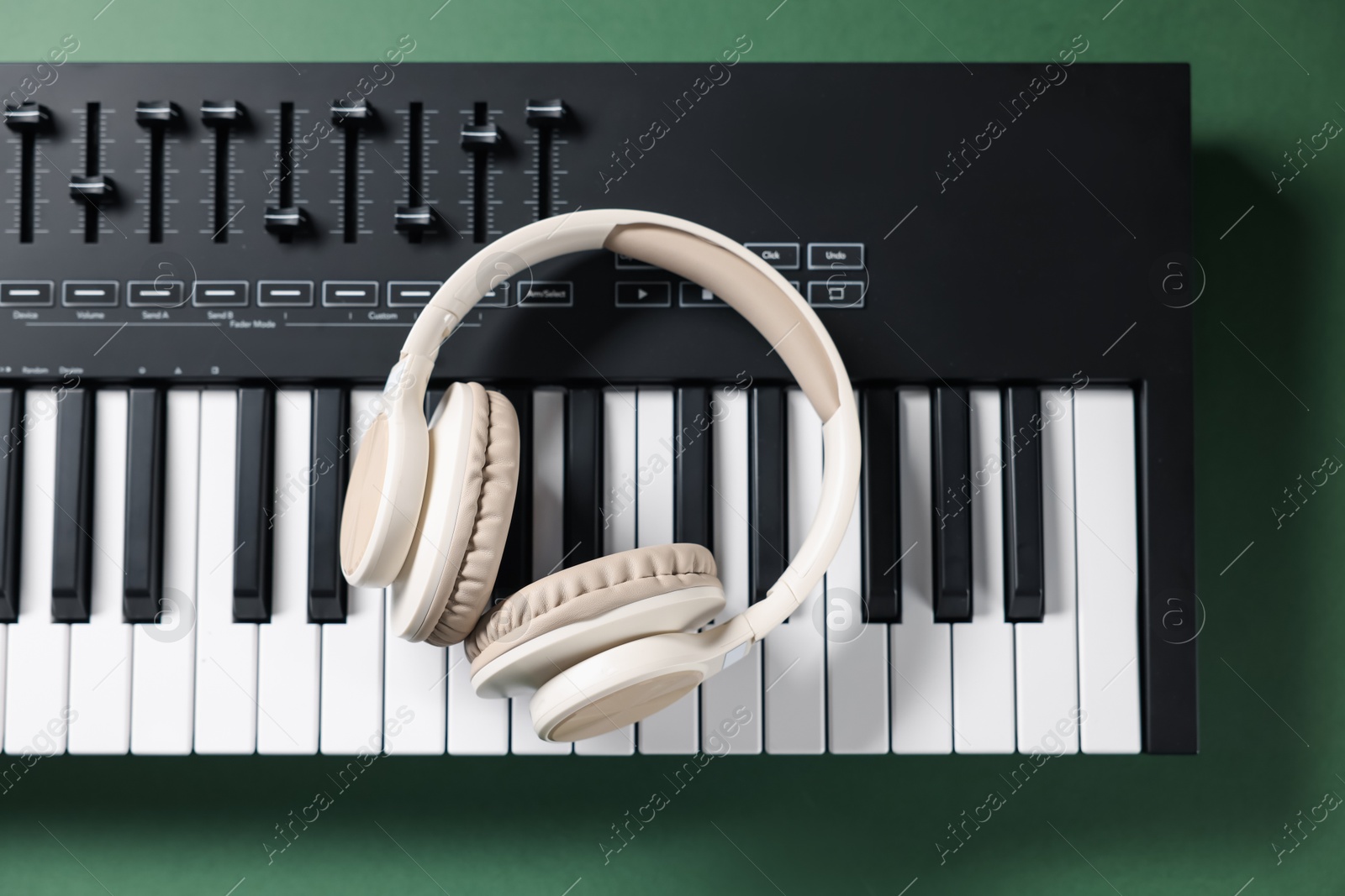 MIDI keyboard and headphones on green background, top view Photo of MIDI keyboard and headphones on green background, top view