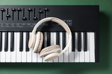 Photo of MIDI keyboard and headphones on green background, top view