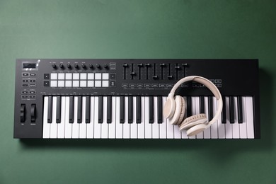 Photo of MIDI keyboard and headphones on green background, top view