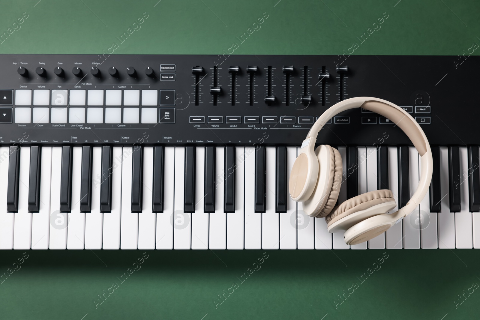 MIDI keyboard and headphones on green background, top view Photo of MIDI keyboard and headphones on green background, top view