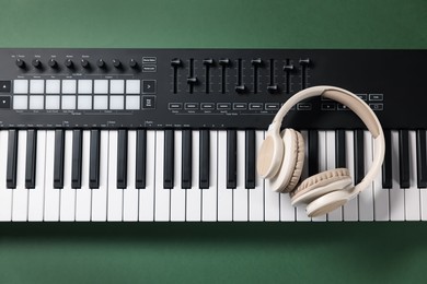 Photo of MIDI keyboard and headphones on green background, top view