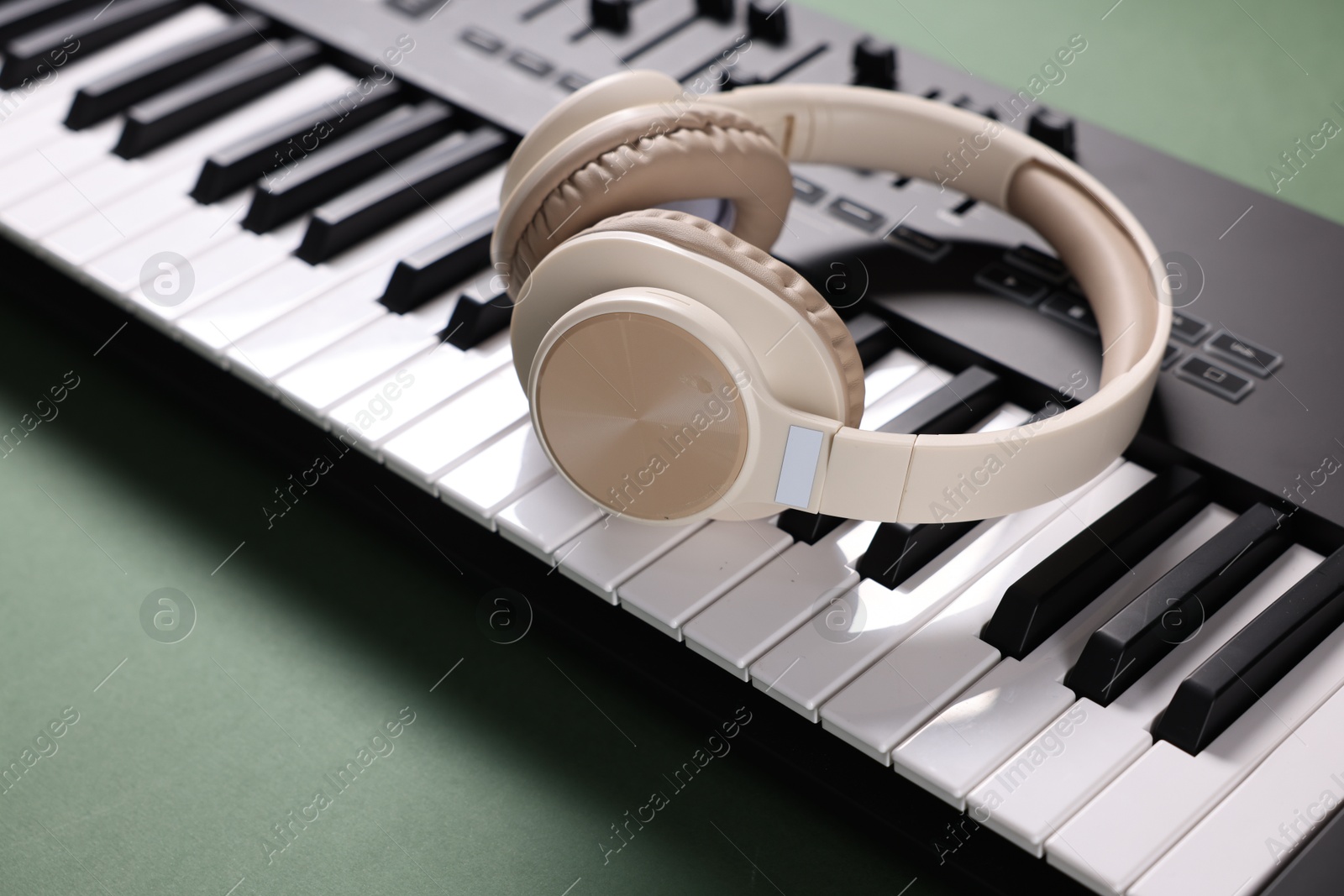 MIDI keyboard and headphones on green background, closeup Photo of MIDI keyboard and headphones on green background, closeup
