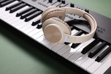 Photo of MIDI keyboard and headphones on green background, closeup