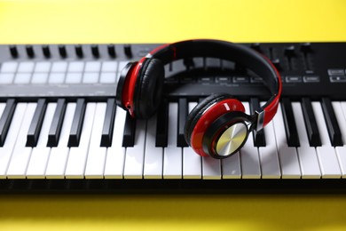Photo of MIDI keyboard with headphones on yellow background, above view