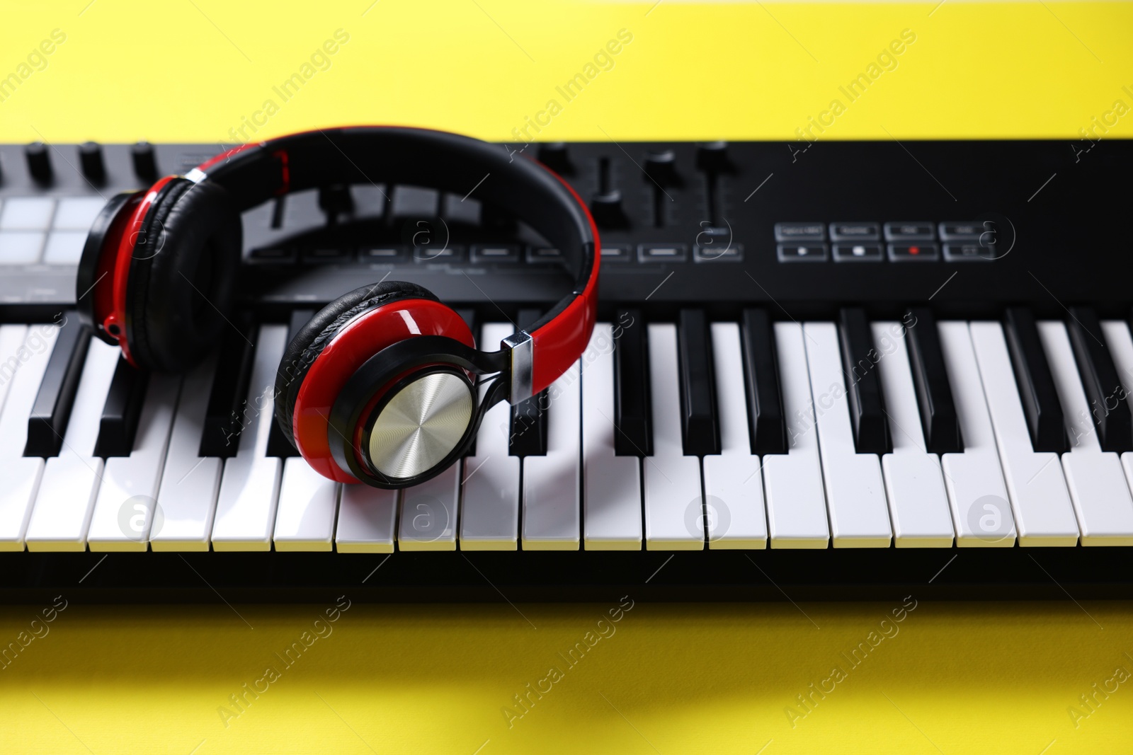 MIDI keyboard with headphones on yellow background, closeup Photo of MIDI keyboard with headphones on yellow background, closeup