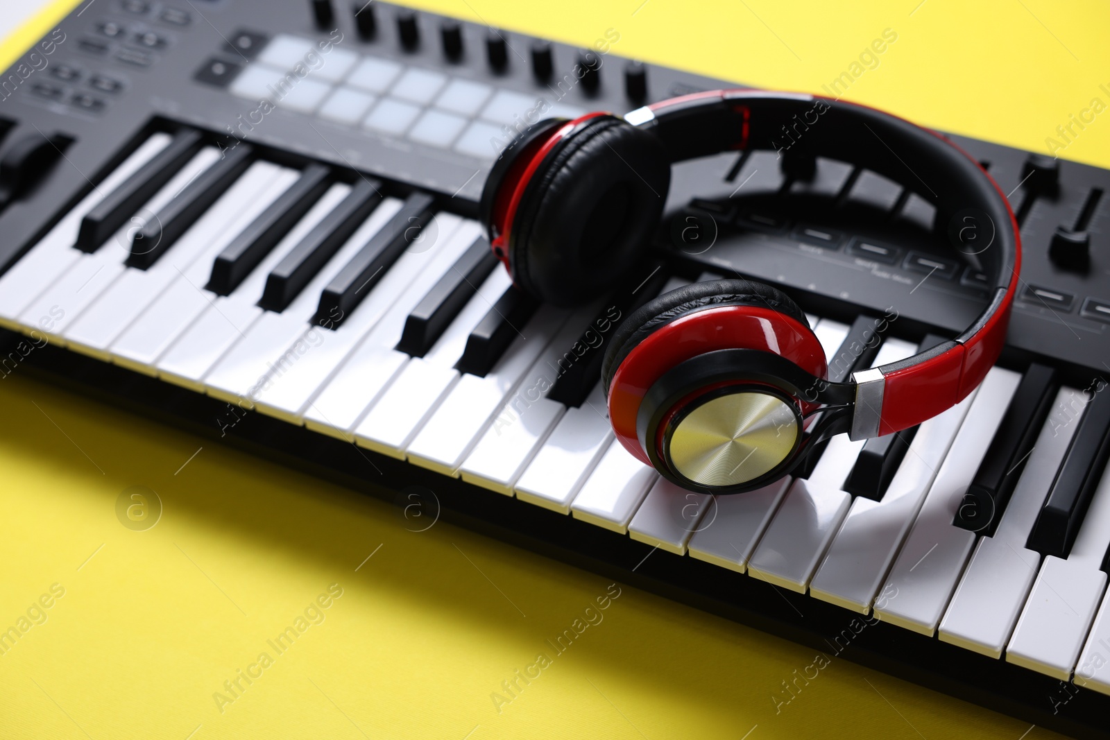 MIDI keyboard with headphones on yellow background, closeup Photo of MIDI keyboard with headphones on yellow background, closeup