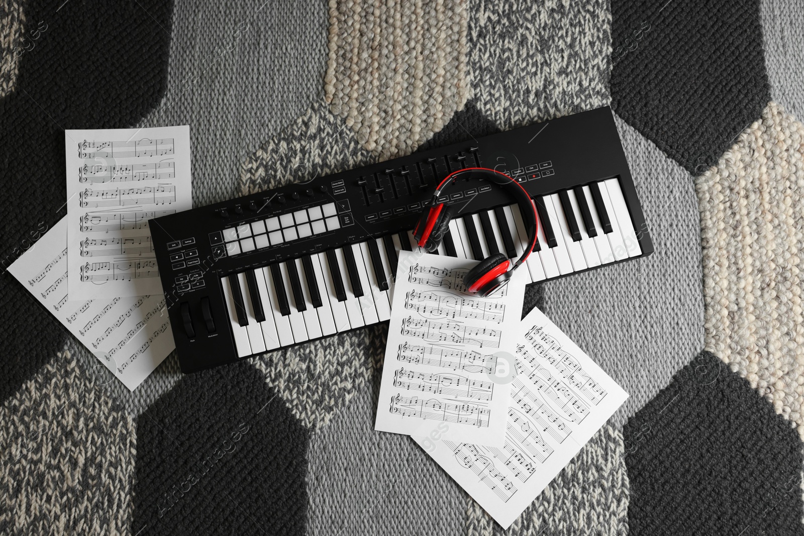 MIDI keyboard, music sheets and headphones on carpet, flat lay Photo of MIDI keyboard, music sheets and headphones on carpet, flat lay