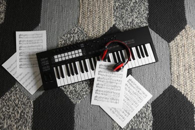 Photo of MIDI keyboard, music sheets and headphones on carpet, flat lay