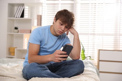 Photo of Teenage boy using smartphone on bed at home