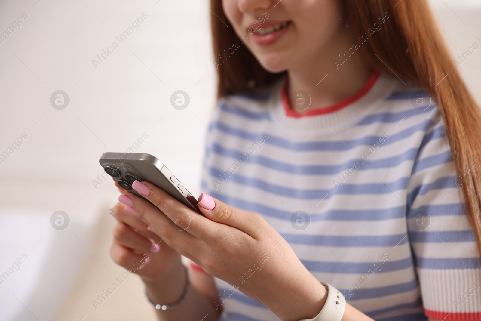 Photo of Smiling teenage girl with smartphone at home, closeup