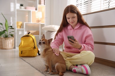 Photo of Teenage girl using smartphone and dog on floor at home
