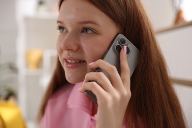 Photo of Smiling teenage girl talking by smartphone at home