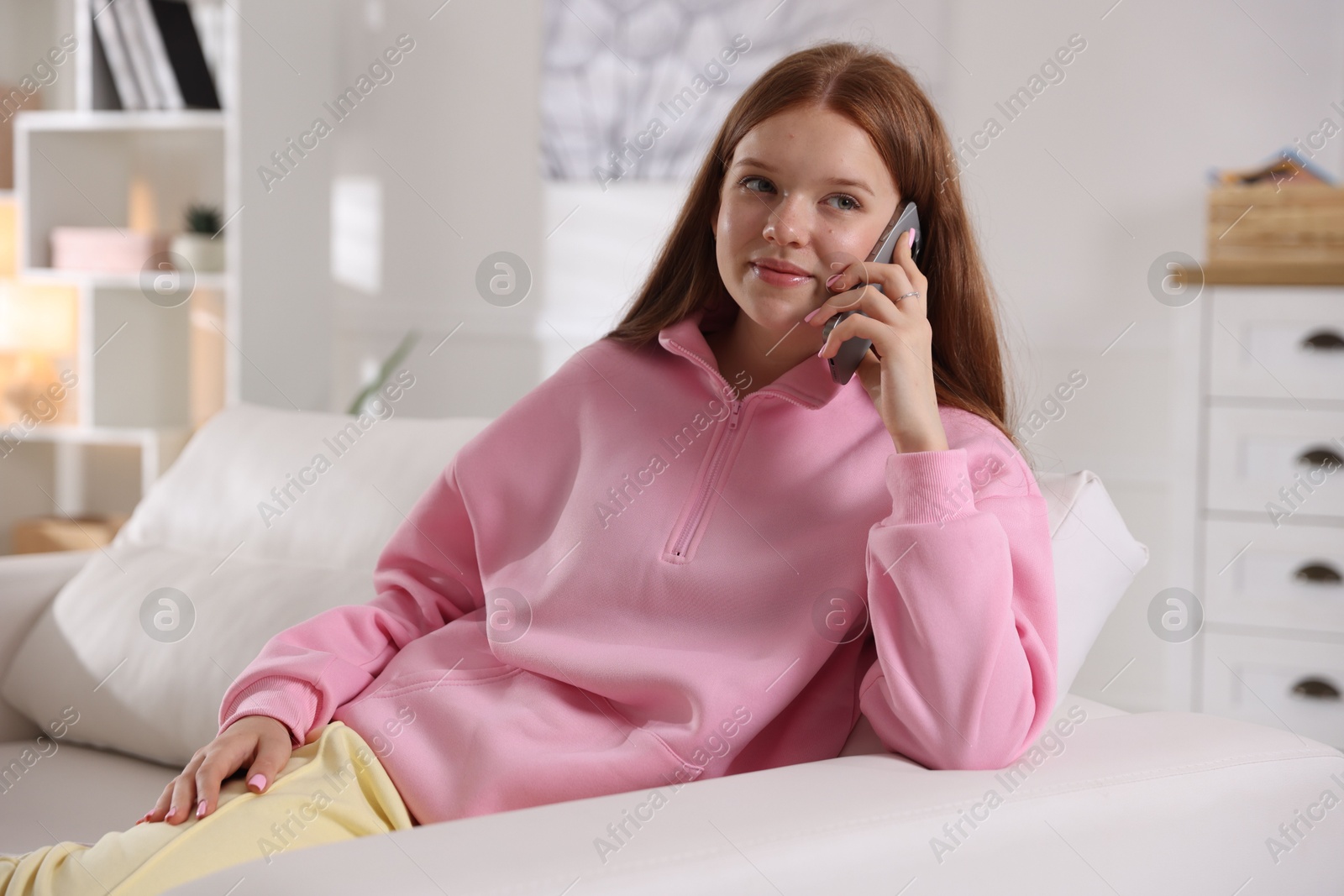 Beautiful teenage girl talking by smartphone on sofa at home Photo of Beautiful teenage girl talking by smartphone on sofa at home