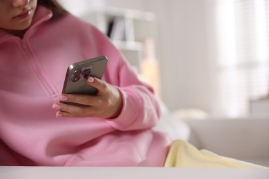 Photo of Teenage girl using smartphone at home, closeup