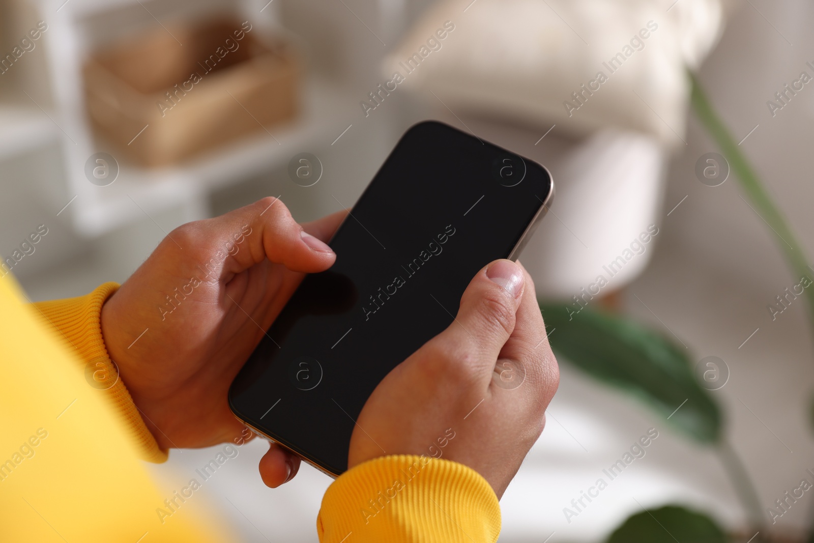 Photo of Teenage boy using smartphone at home, closeup