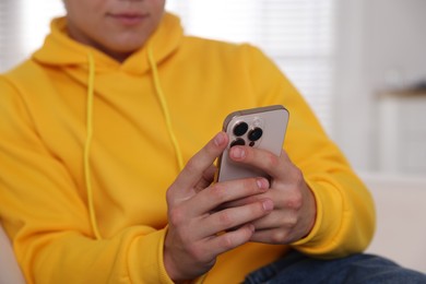 Photo of Teenage boy using smartphone at home, closeup