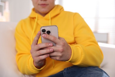 Photo of Teenage boy using smartphone at home, closeup