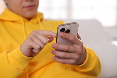 Photo of Teenage boy using smartphone at home, closeup