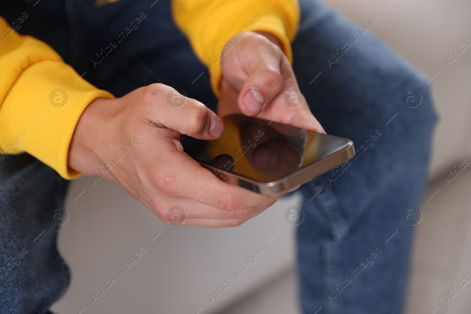 Photo of Teenage boy using smartphone at home, closeup