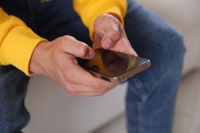 Photo of Teenage boy using smartphone at home, closeup