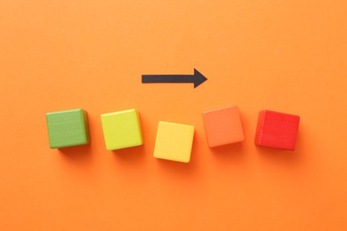 Photo of Maximum. Colorful cubes and arrow on orange background, flat lay