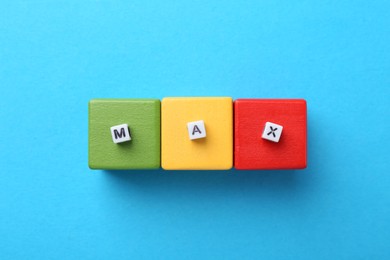 Photo of Colorful cubes and word Max with letters on light blue background, top view