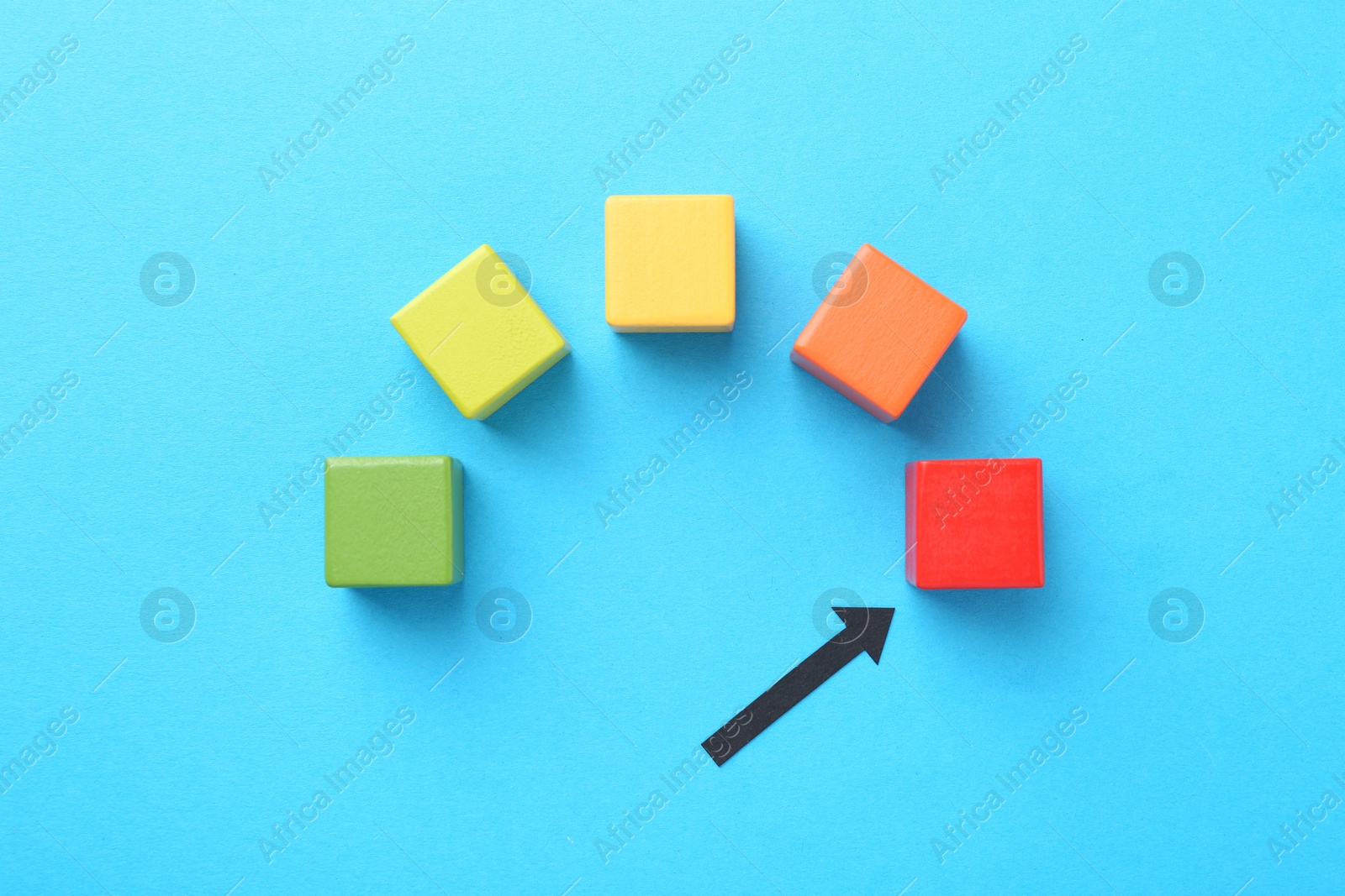 Maximum. Colorful cubes and arrow pointing at red one on light blue background, flat lay Photo of Maximum. Colorful cubes and arrow pointing at red one on light blue background, flat lay