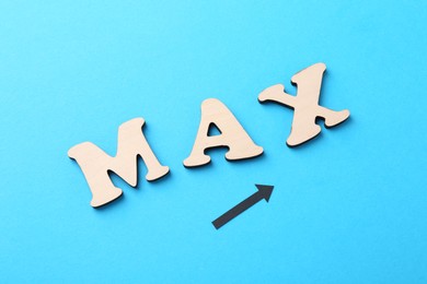 Photo of Word Max made of wooden letters and arrow on light blue background, flat lay