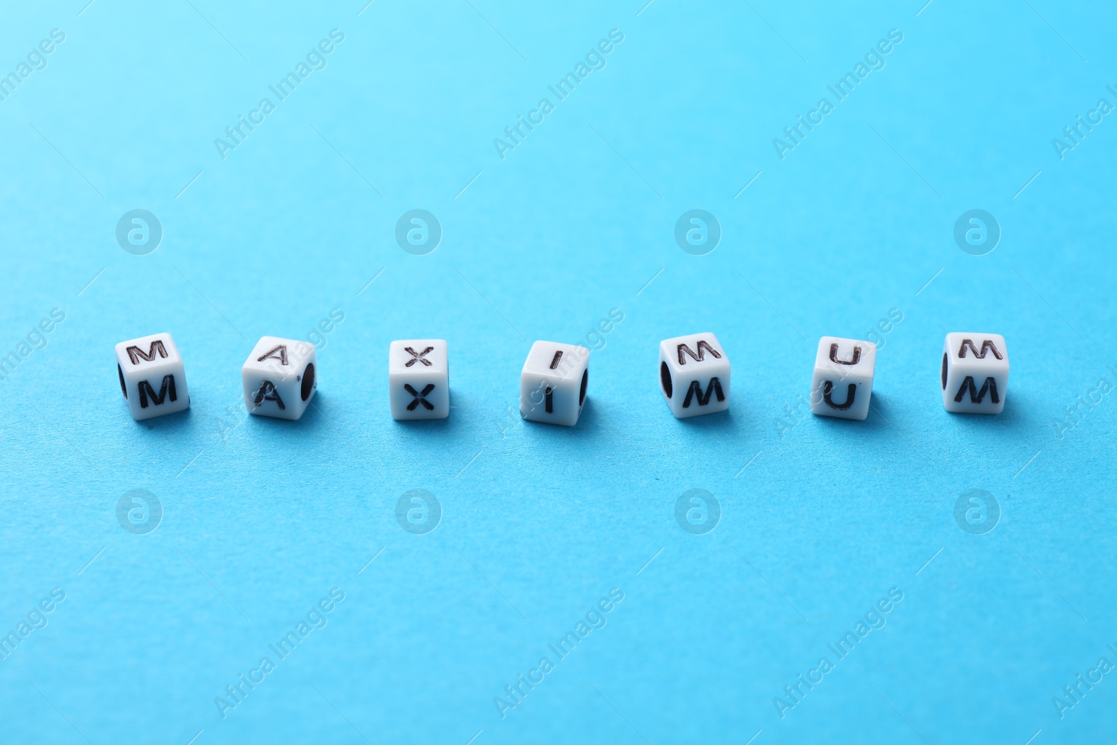 Word Maximum made of beads with letters on light blue background, closeup Photo of Word Maximum made of beads with letters on light blue background, closeup