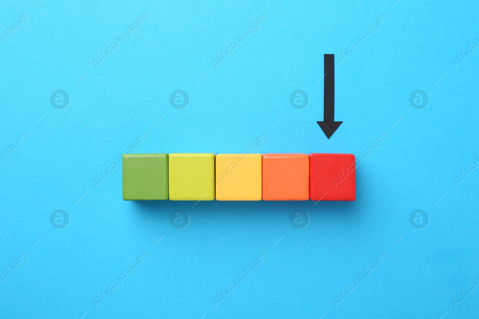 Maximum. Colorful cubes and arrow pointing at red one on light blue background, flat lay Photo of Maximum. Colorful cubes and arrow pointing at red one on light blue background, flat lay