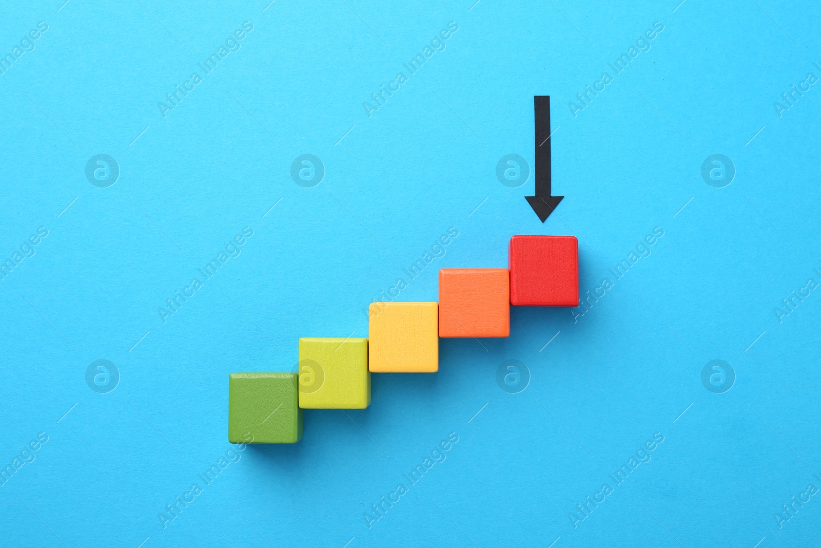 Maximum. Colorful cubes and arrow pointing at red one on light blue background, flat lay Photo of Maximum. Colorful cubes and arrow pointing at red one on light blue background, flat lay