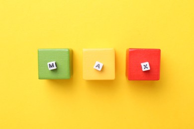 Photo of Colorful cubes and word Max on yellow background, top view