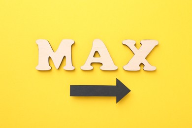 Photo of Word Max made of wooden letters and arrow on yellow background, flat lay