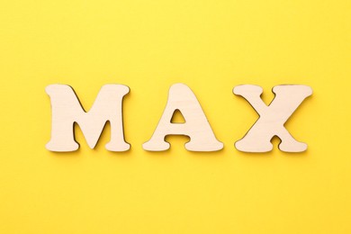 Photo of Word Max made of wooden letters on yellow background, top view