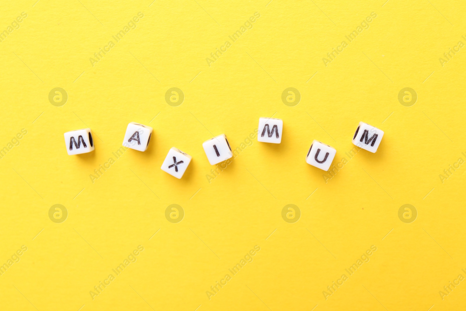 Word Maximum made of beads with letters on yellow background, top view Photo of Word Maximum made of beads with letters on yellow background, top view