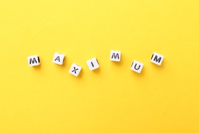Photo of Word Maximum made of beads with letters on yellow background, top view