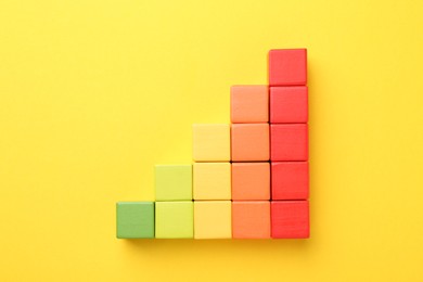 Photo of Maximum. Colorful cubes on yellow background, flat lay