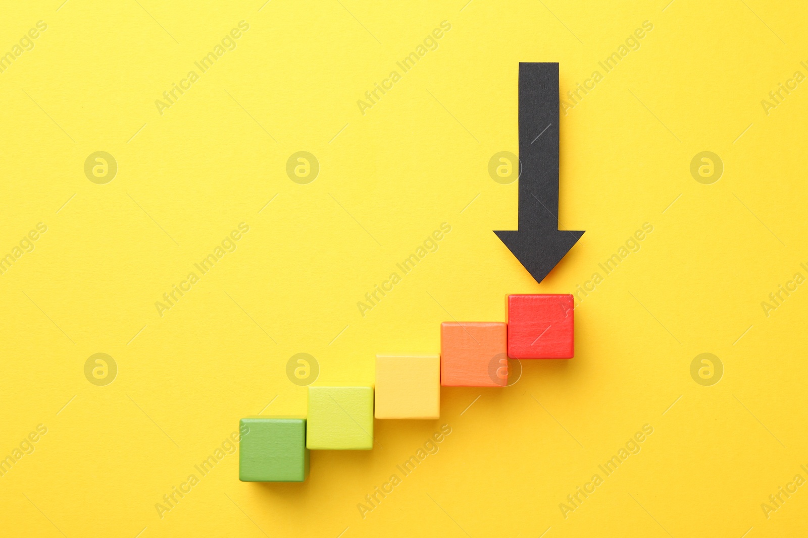 Maximum. Colorful cubes and arrow pointing at red one on yellow background, flat lay Photo of Maximum. Colorful cubes and arrow pointing at red one on yellow background, flat lay