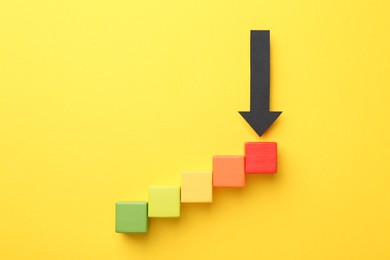 Photo of Maximum. Colorful cubes and arrow pointing at red one on yellow background, flat lay