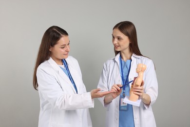 Photo of Medical students with human body model on light grey background