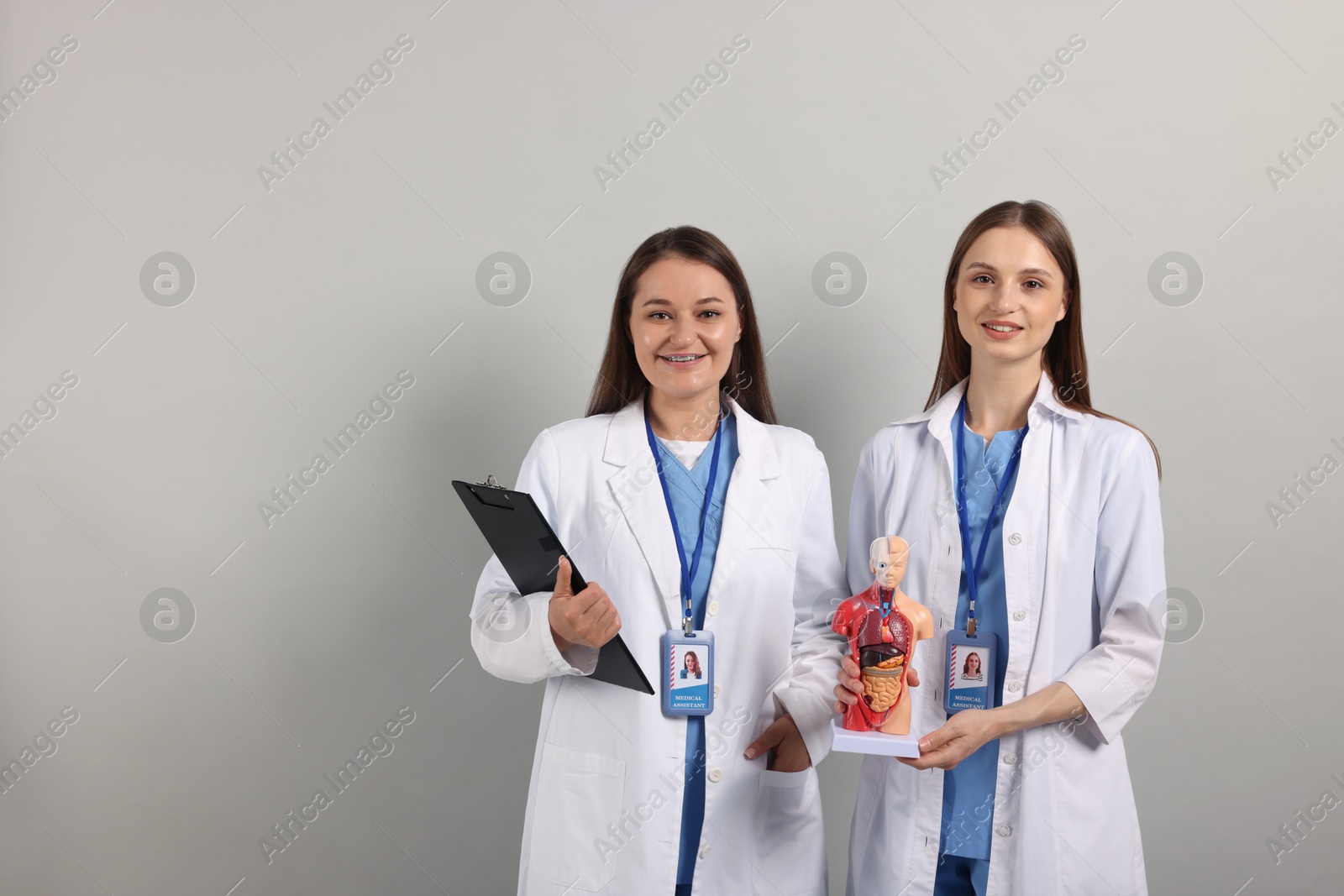 Photo of Medical students with human body model and clipboard on light grey background. Space for text
