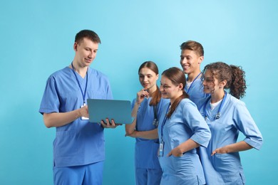 Photo of Group of medical students with laptop on light blue background