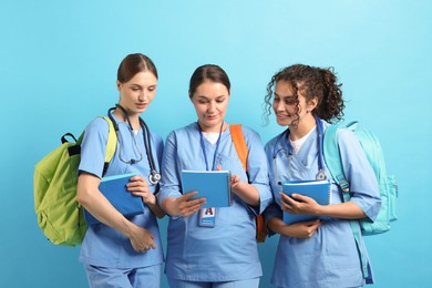 Photo of Group of medical students with books on light blue background
