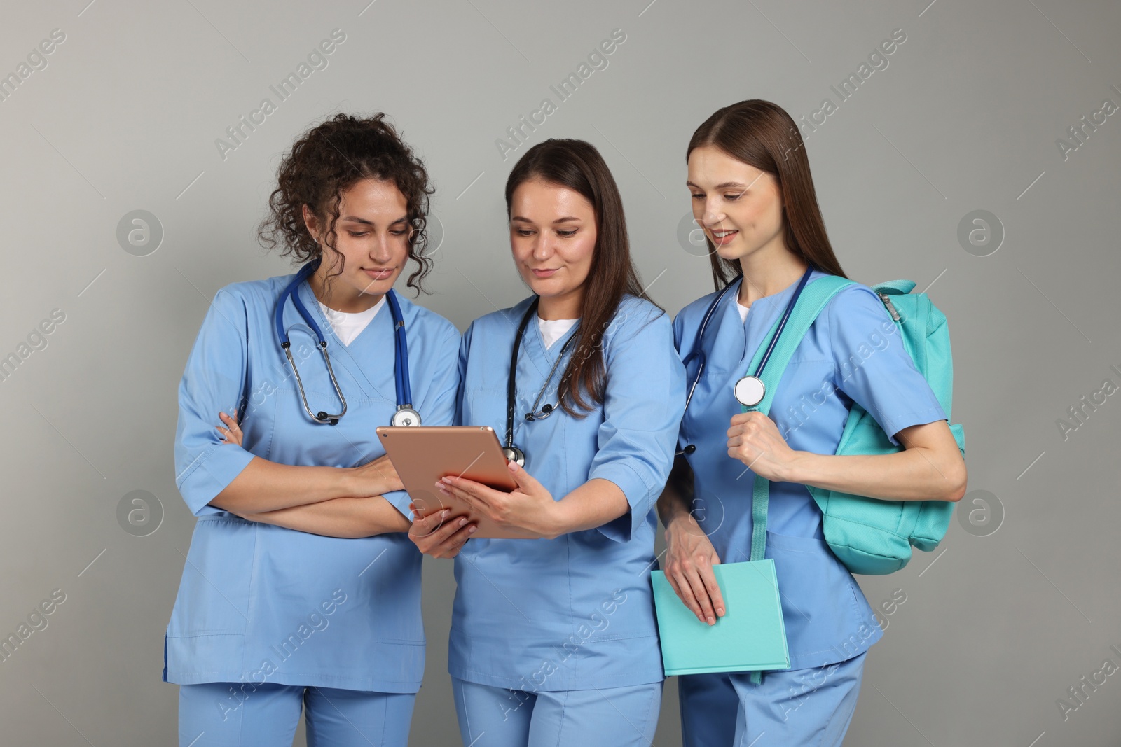 Photo of Group of medical students with tablet on light grey background