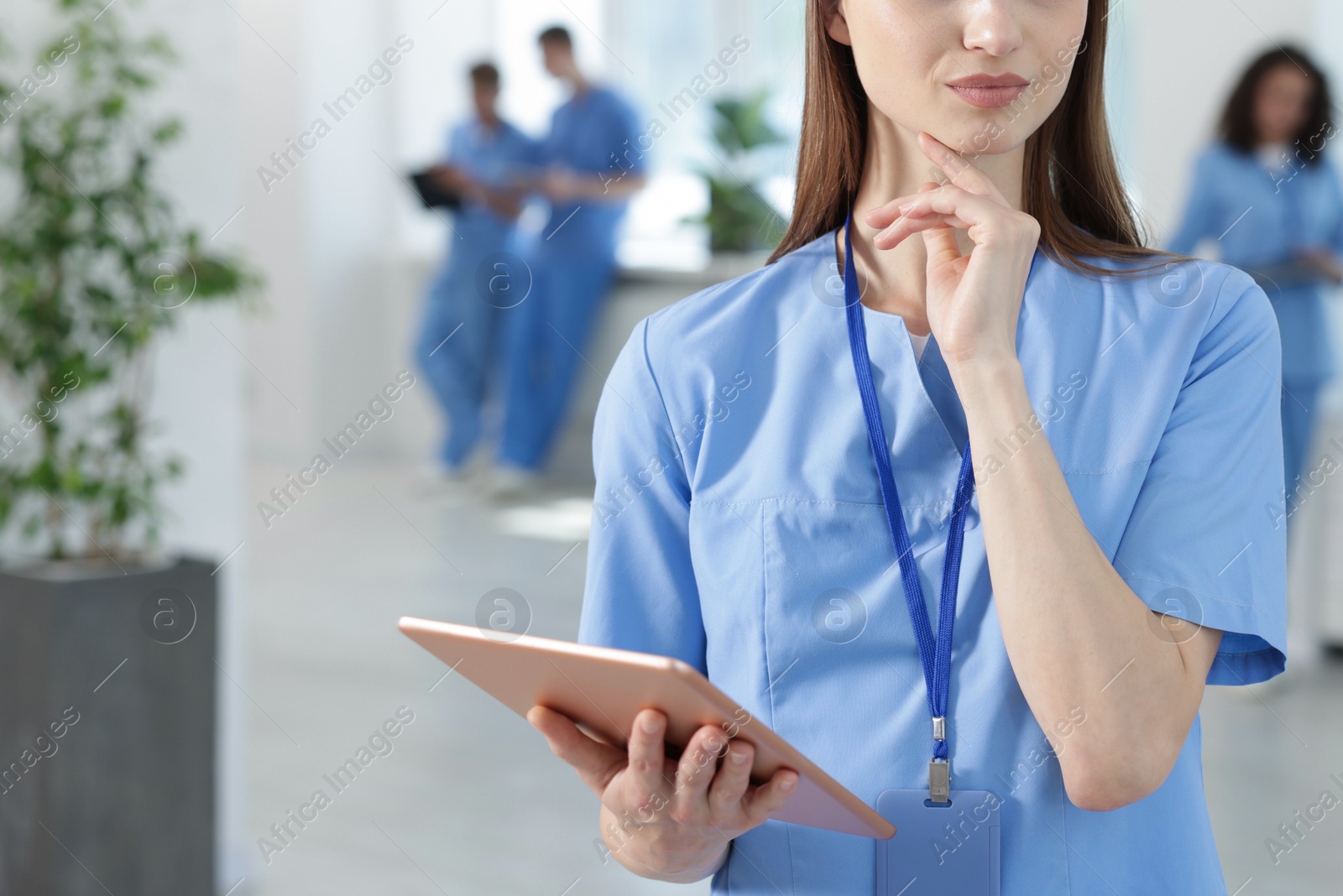 Photo of Medical student in uniform with tablet indoors, selective focus