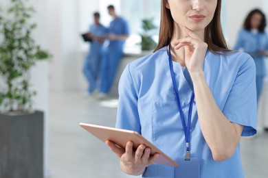 Photo of Medical student in uniform with tablet indoors, selective focus