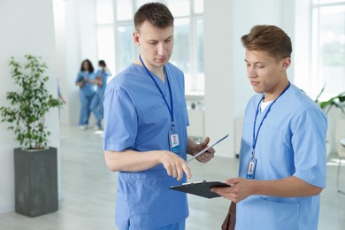 Photo of Medical students in uniforms studying together indoors, selective focus