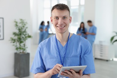 Photo of Medical student in uniform with tablet indoors, selective focus